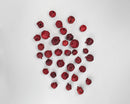 Bulk dried natural pomegranate seeds in deep red scattered on white background.