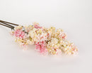 A bundle of artificial lilac spray stems with pink cream colored flowers on a white background.