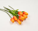 A bundle of artificial orange tulips with green leaves, tied together.